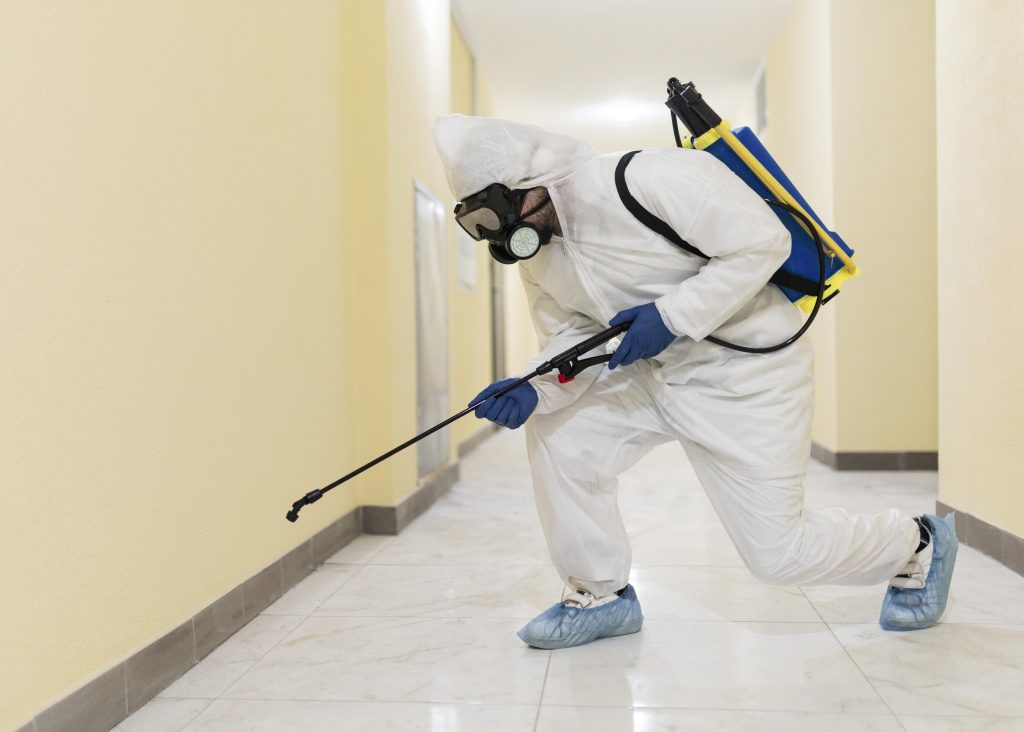 full shot man disinfecting building (1)